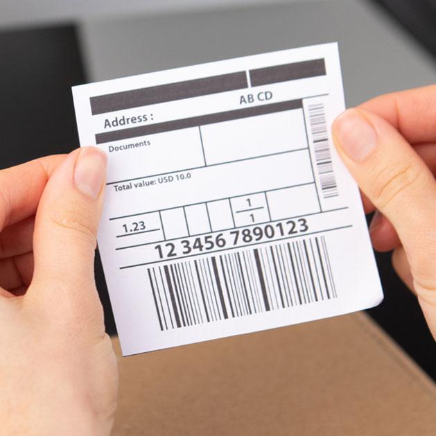 etticketierung-b Zeitarbeiter in Norderstedt klebt präzise Versandetikett auf Paket für Nordheide Logistik.